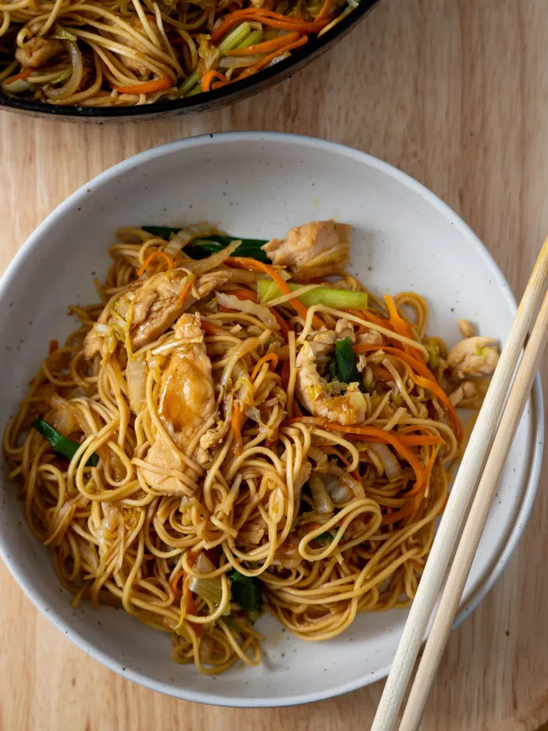 Chicken Lo Mein noodles plated in a bowl with chopsticks.