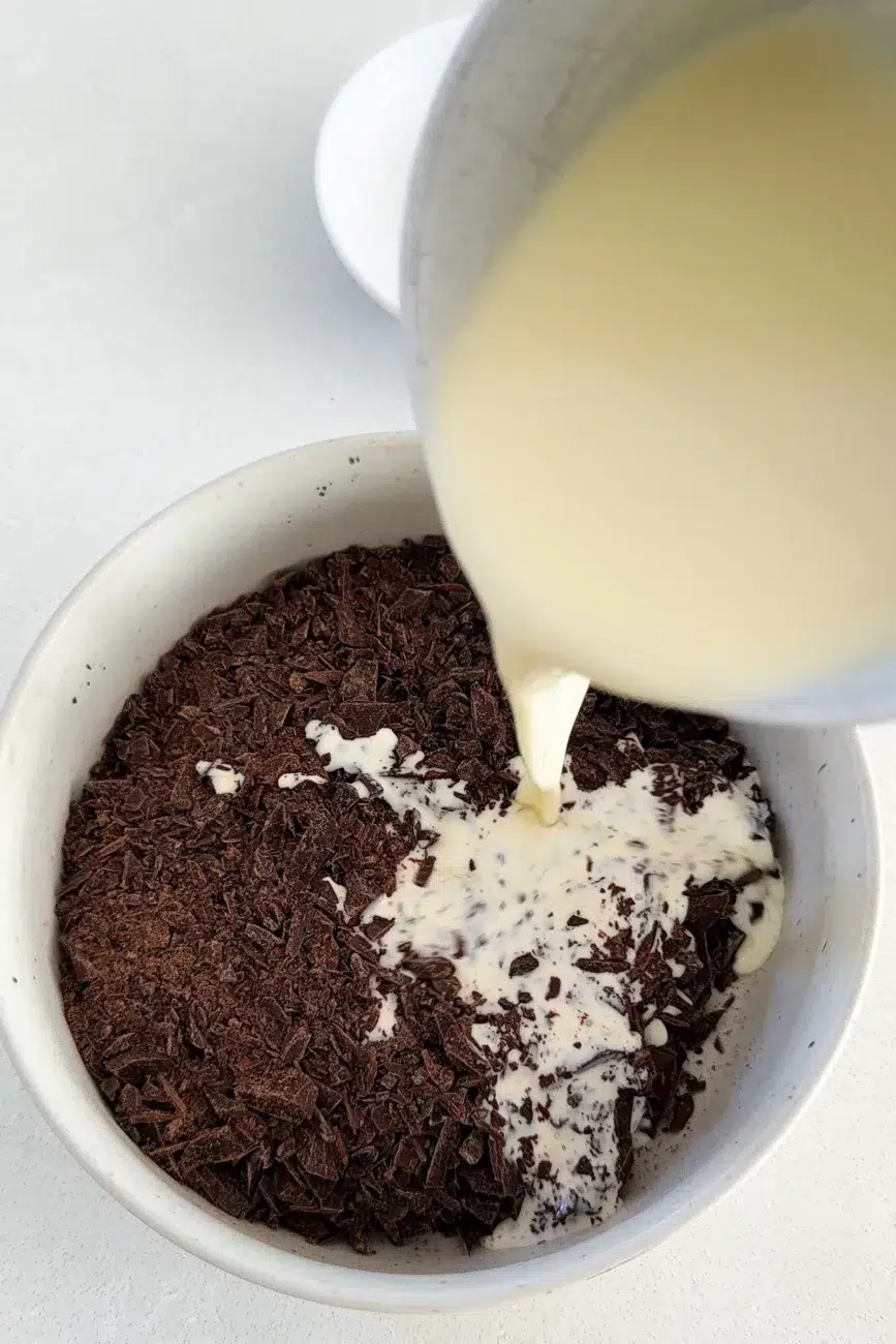 Making the chocolate ganache hot cream being poured into the finely chopped chocolate