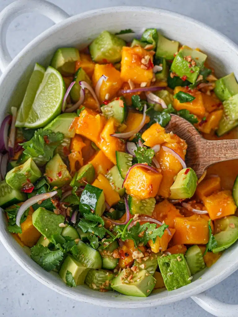 Close-up of a spoon scooping Mango Salad with Sweet Chilli Lime Dressing from a bowl