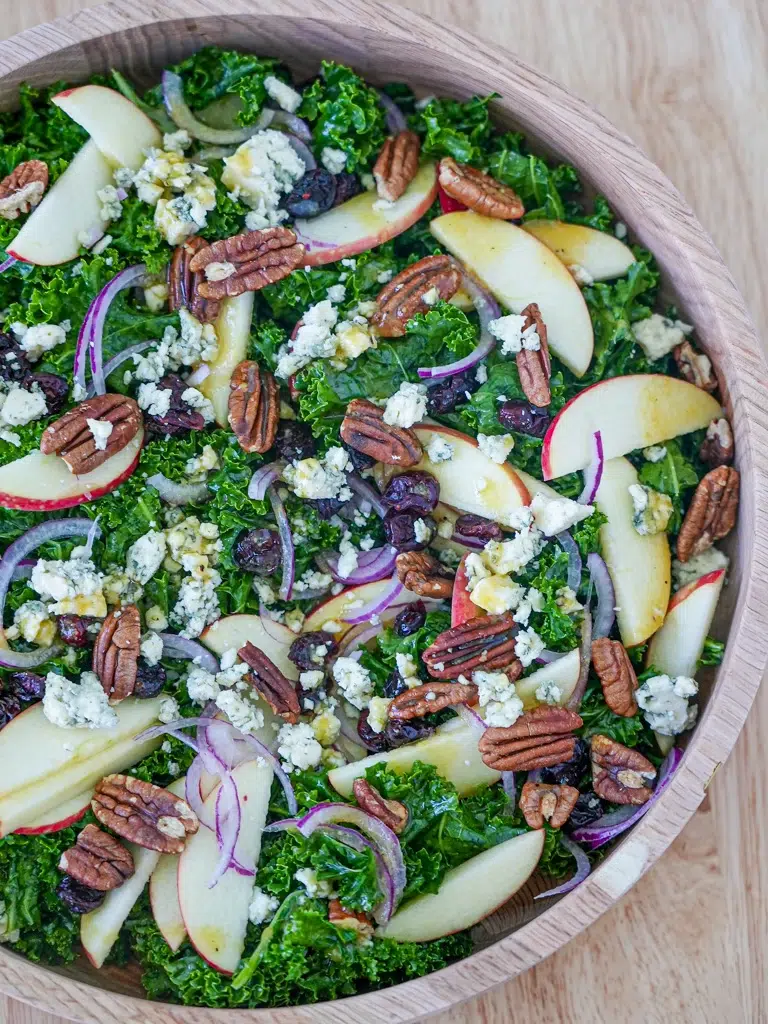 Overhead view of a bowl of maple kale salad with dried cranberries and blue cheese.