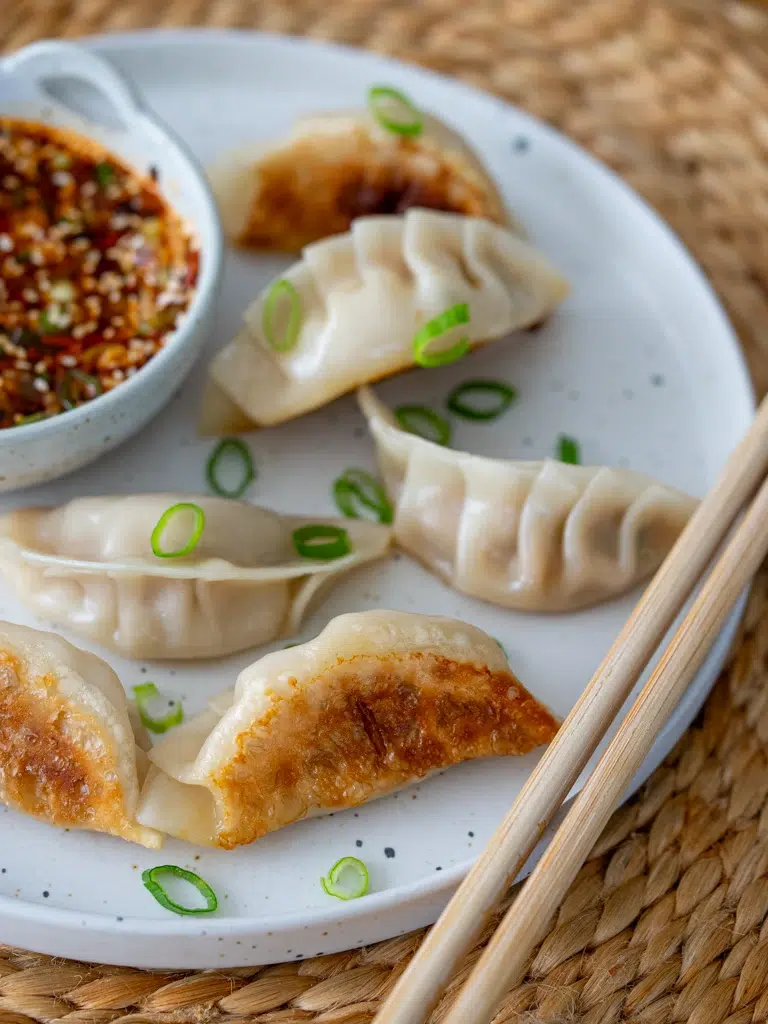 Sideways-plated pork and cabbage dumplings with chopsticks resting beside them