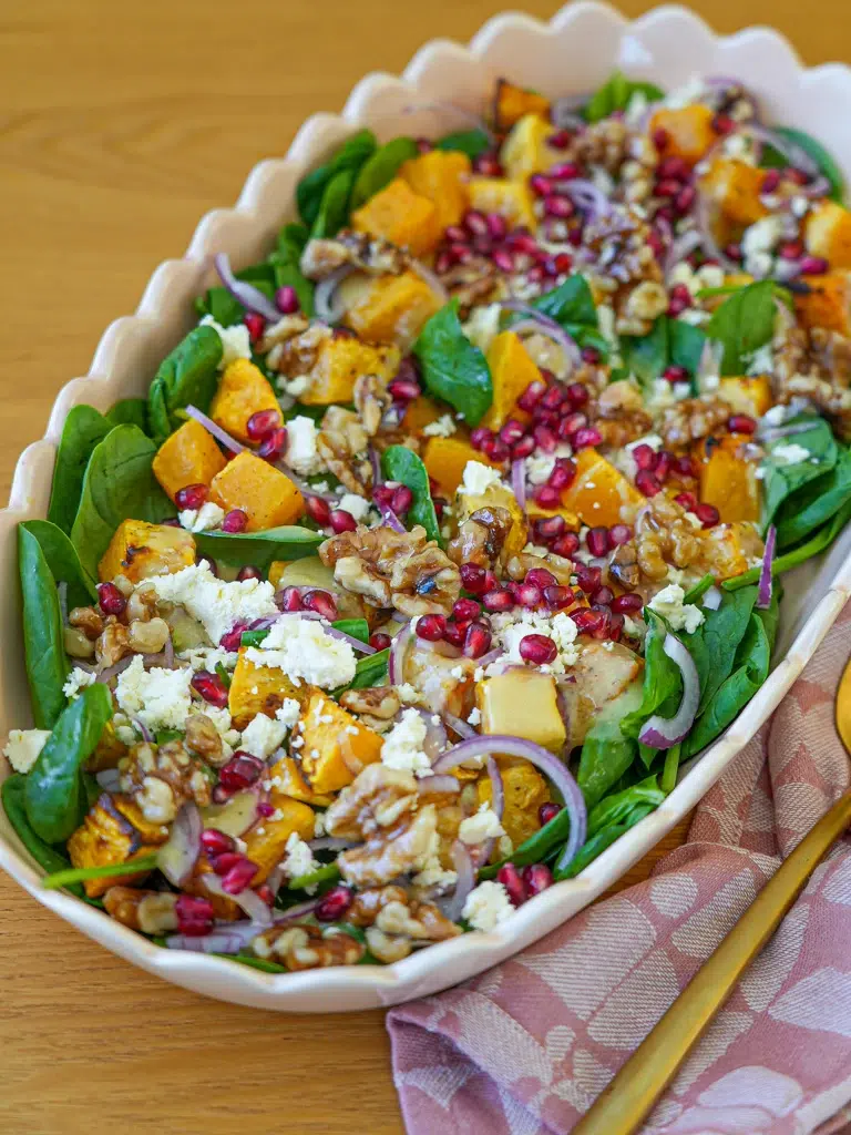 Freshly prepared roast pumpkin salad with creamy feta and crunchy candied walnuts in a bowl.